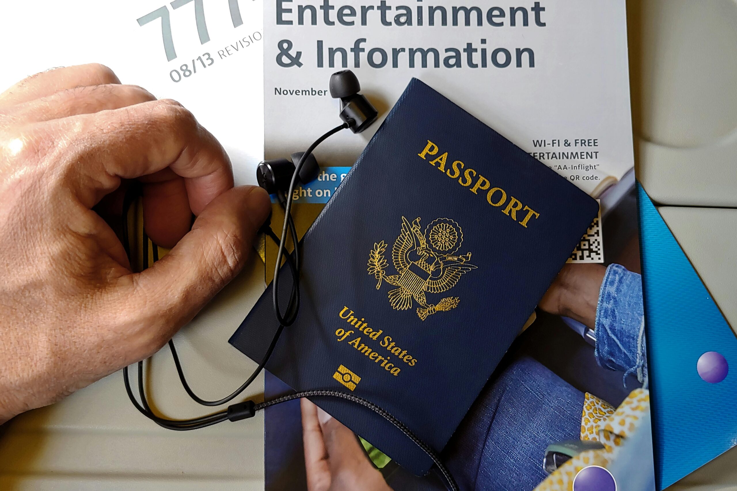 Close up of a Hand next to an American Passport with Headphones